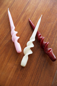 glossy spiral taper candles by &klevering in pink cream and deep red on oak table
