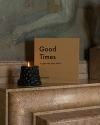 Good Times small photo album styled on marble fireplace with black candle
