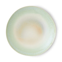 Round ceramic plate with a gradient color from green to beige on a white background