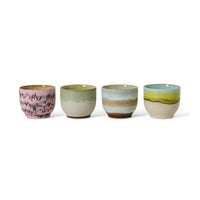 Set of four ceramic cups with different color patterns on a white background