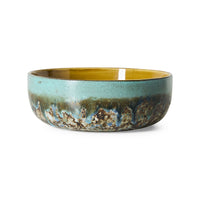 A 70s ceramic bowl with a textured, rustic glaze featuring a turquoise blue exterior, a dark brown and black mottled lower section, and a warm ochre yellow interior, shown on a plain white background.