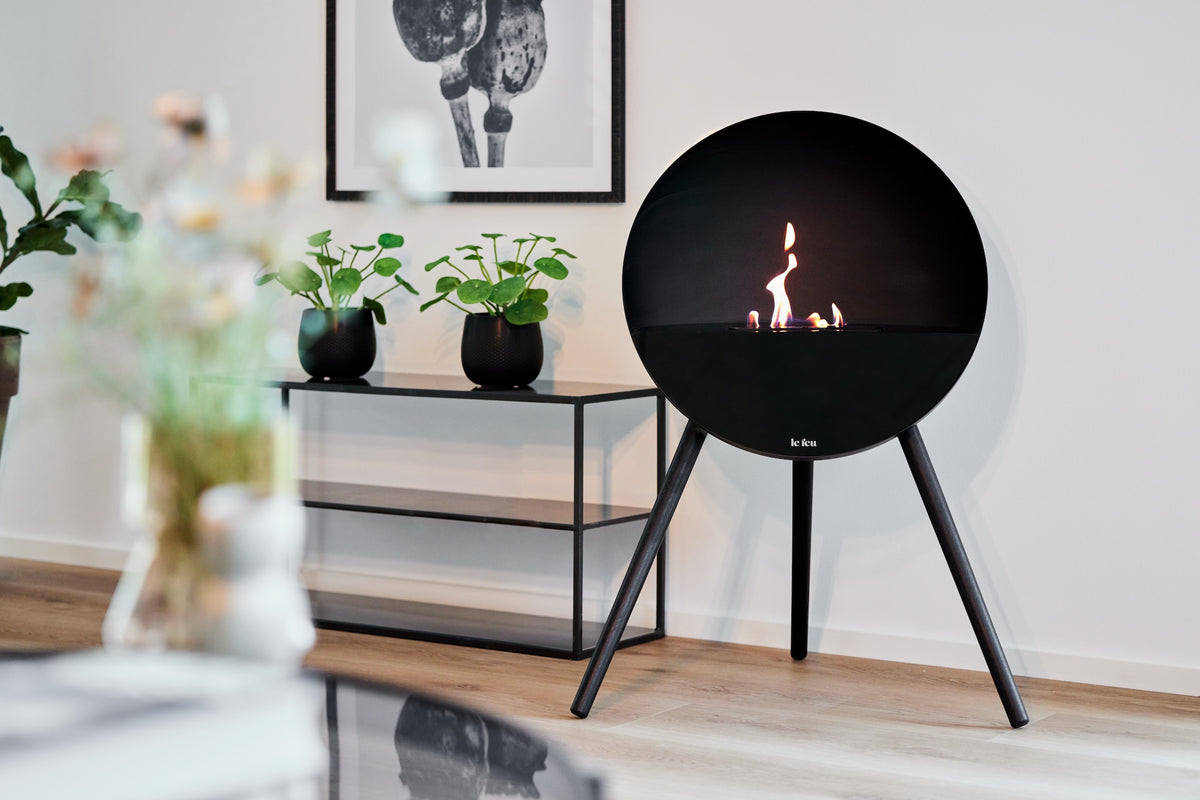 Le Feu Eye bioethanol fireplace in matte black with black oak legs adding modern Nordic warmth to a minimalist interior