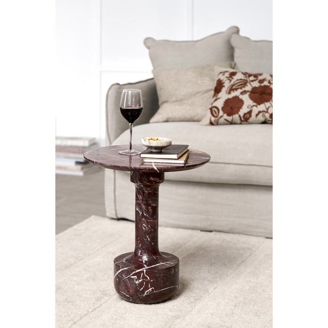 Burgundy Marel marble side table beside a cream sofa with a glass of red wine and books