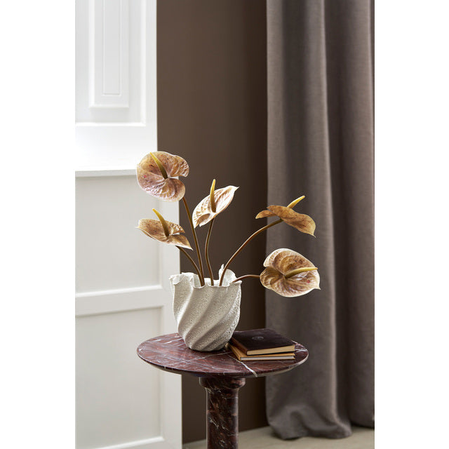Burgundy marble side table styled with a white vase of dried anthurium flowers by a window