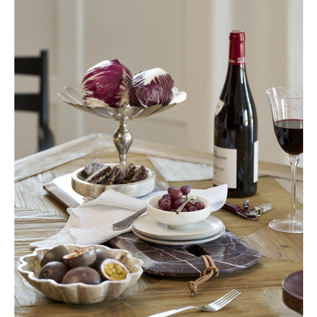 Burgundy Marnine marble board on a dining table with red wine, radicchio and serving bowls