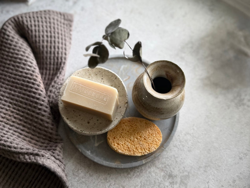 Soap dish styled in calm bathroom setting with eucalyptus and natural sponge