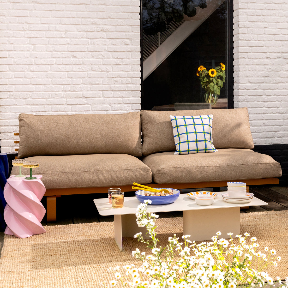 lifestyle shot of beige sofa with a set up including sald ready to be served with striped &Klevering salad servers