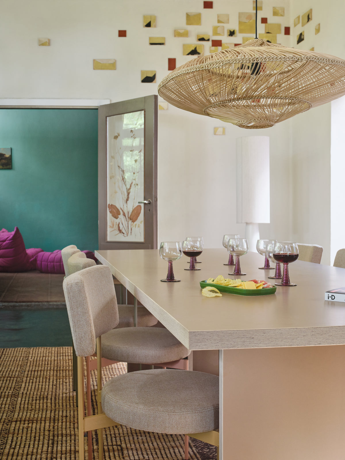 Long cream HKLIVING rectangular dining table with upholstered chairs under a rattan pendant in a room with a teal wall