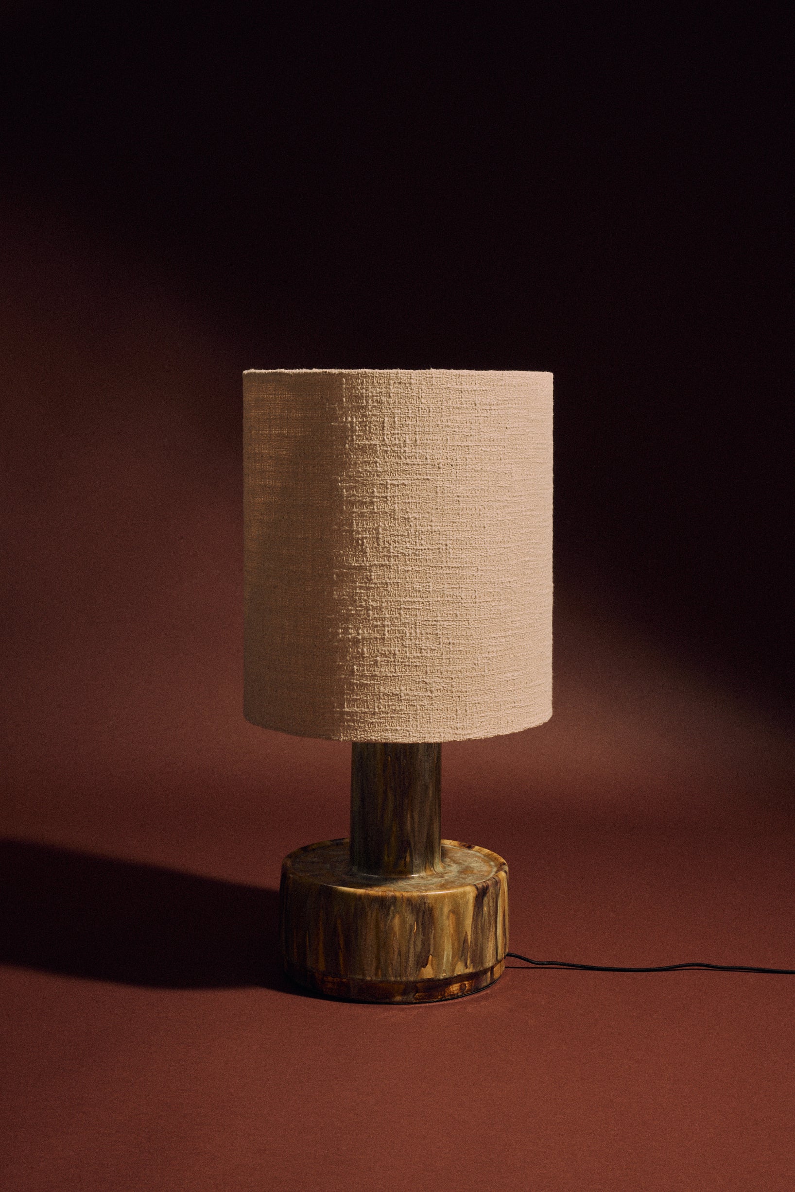 Ceramic lamp base in reactive green glaze on white background, base only