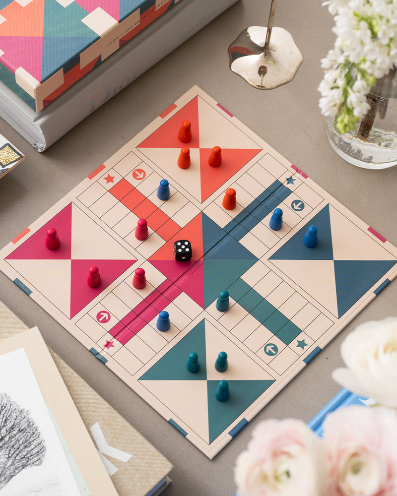Open Ludo board in play with colourful pieces