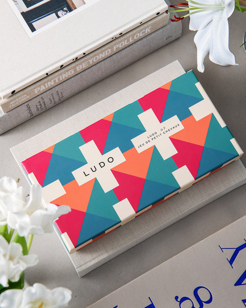 Ludo game styled on a coffee table with books and flowers