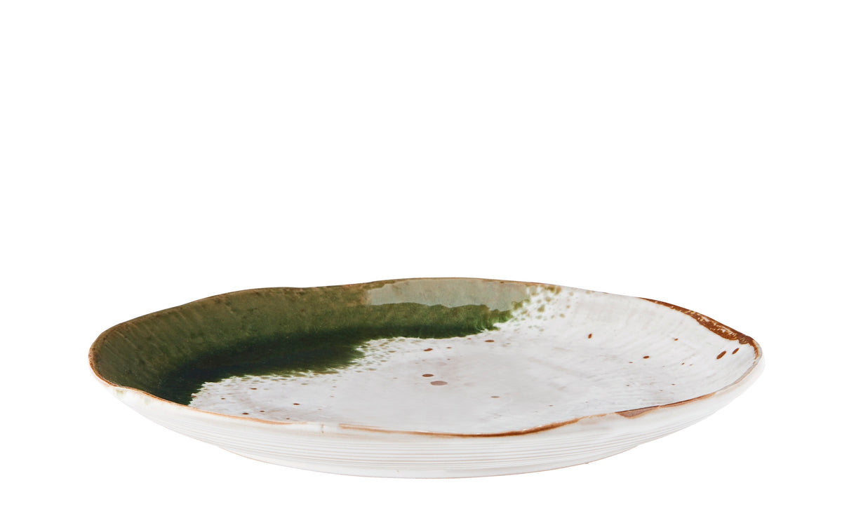 side view of white and green stoneware dinner plate showing curved edge
