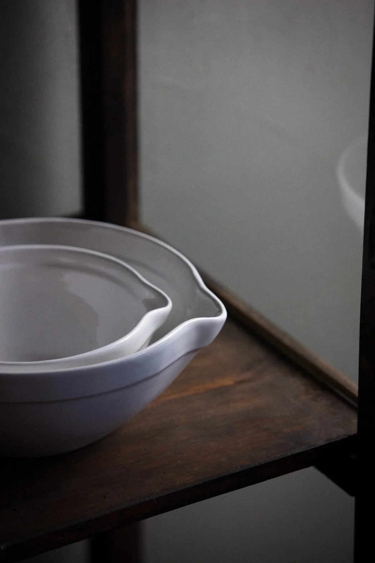 Majken white stoneware bowls by Olsson & Jensen stacked on a dark wooden shelf