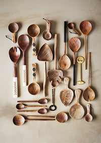 collection of various handcrafted wooden kitchen utensils laid out on neutral background