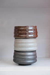 stacked handmade stoneware matcha bowls showing bark brown glaze and earthy textures