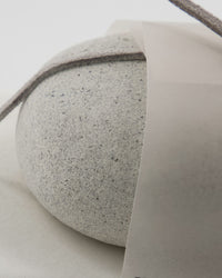 Close-up of the textured grey Meraki scrub stone and its label band