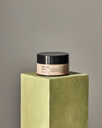 Meraki body scrub in Northern Dawn fragrance displayed on pedestal for minimalist skincare aesthetic
