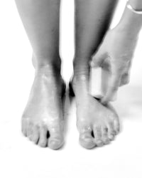 Black and white image of bare feet, showing the stone scrub used as a foot care ritual