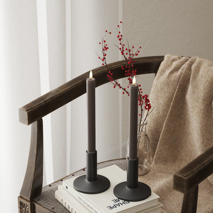 Mocha LED dinner candles on a wooden chair with red berries and a soft throw, adding cosy seasonal light to a corner.
