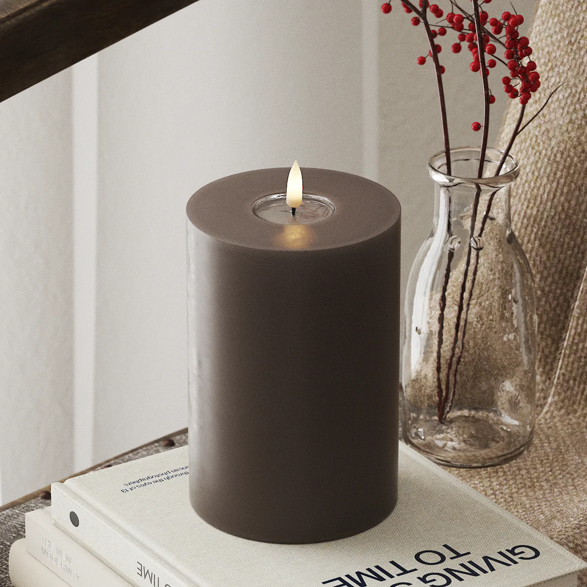 large mocha LED pillar candle glowing in a warm winter interior
