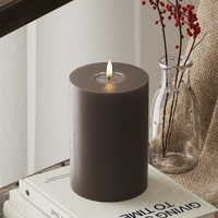 large mocha LED pillar candle glowing in a warm winter interior
