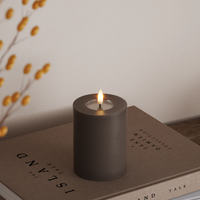 mocha wax-coated LED pillar candle with warm lifelike flame styled on books for autumn décor
