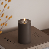 tall mocha LED pillar candle with flickering flame styled beside autumn foliage
