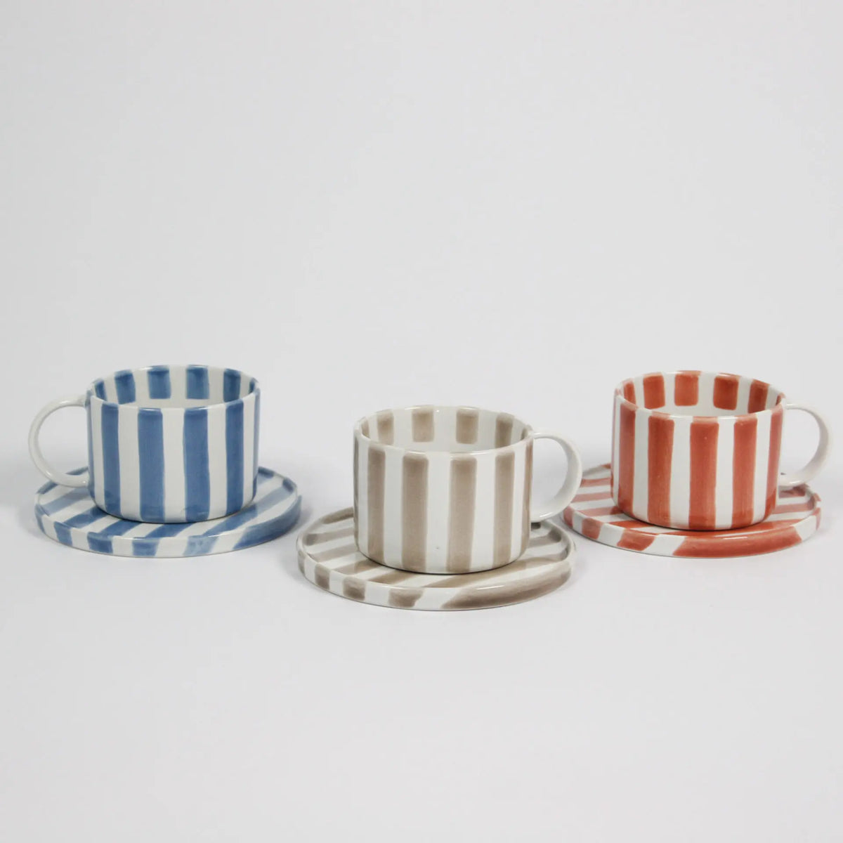 Row of Monica striped cups and saucers by Olsson & Jensen in blue, beige and rust