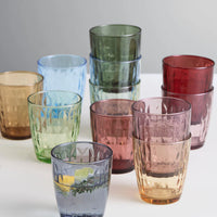 Set of multicolored Aida glass tumblers on a white surface with a light gray background