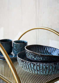 reactive glaze petrol green stoneware bowls stacked on brass serving trolley
