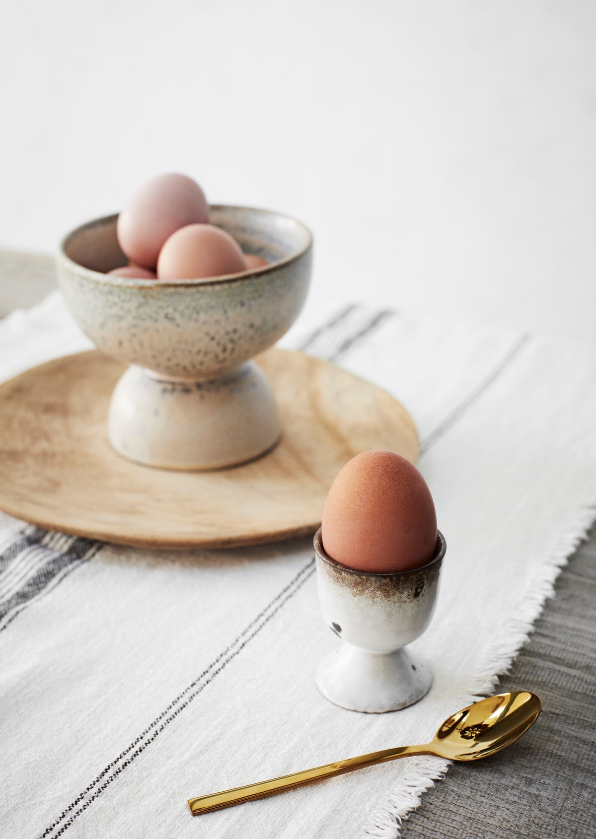 speckled stoneware egg cups styled on a breakfast table
