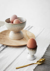 speckled stoneware egg cups styled on a breakfast table
