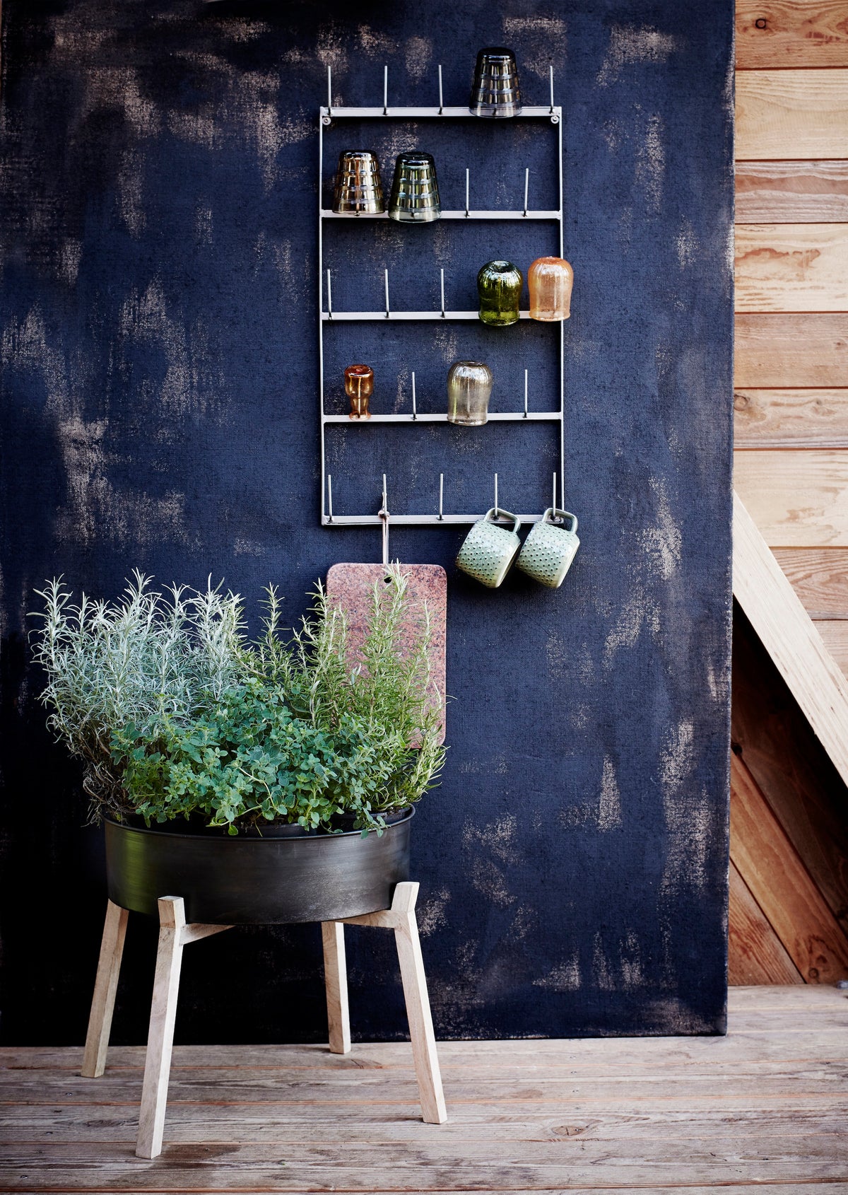 green stoneware mug with dots styled on a wall rack with ceramics
