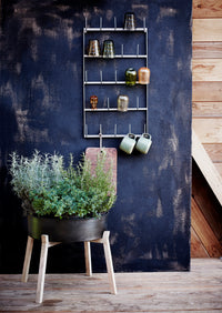 green stoneware mug with dots styled on a wall rack with ceramics
