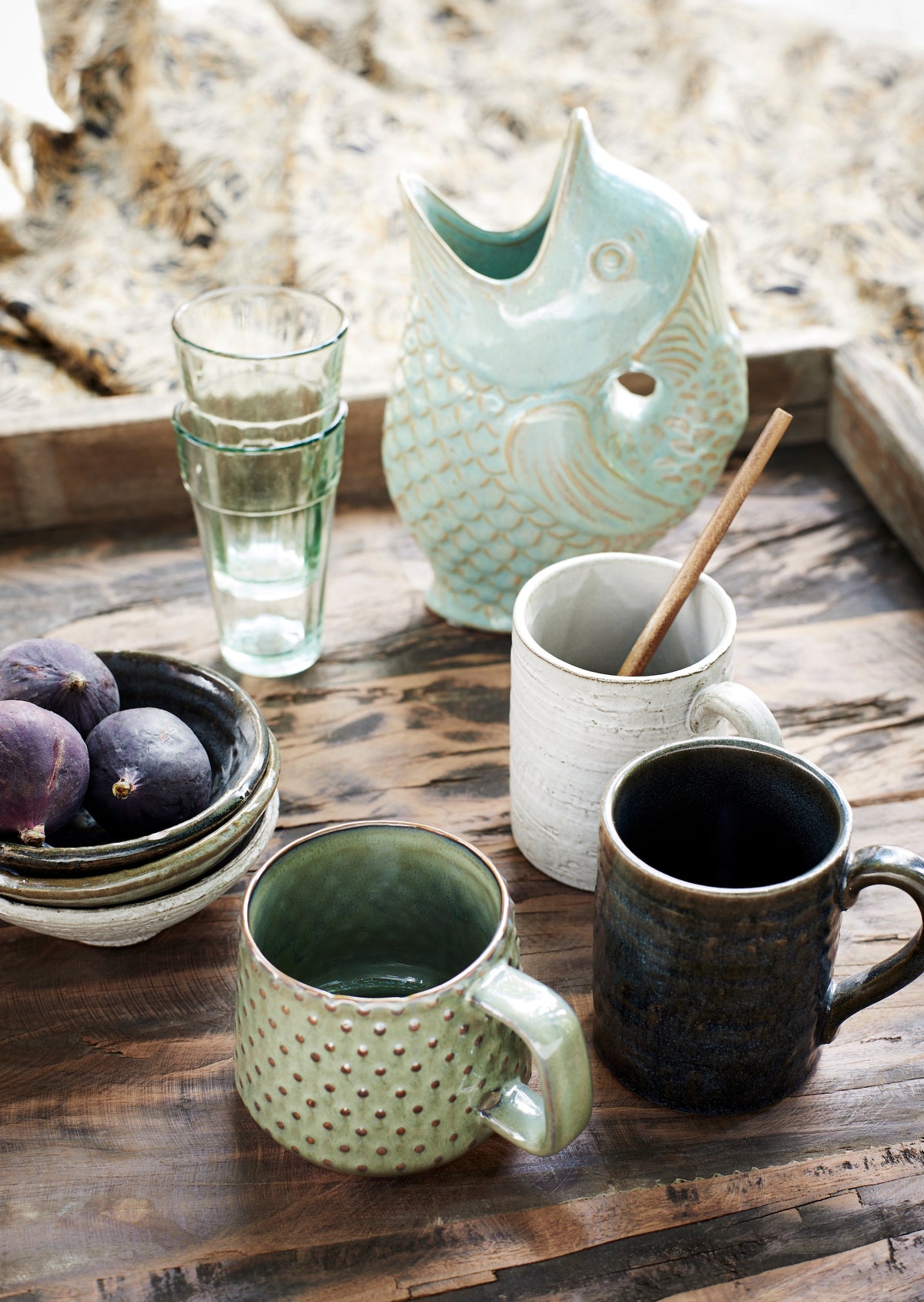 Ceramic mugs and a pitcher on a wooden surface with a natural background