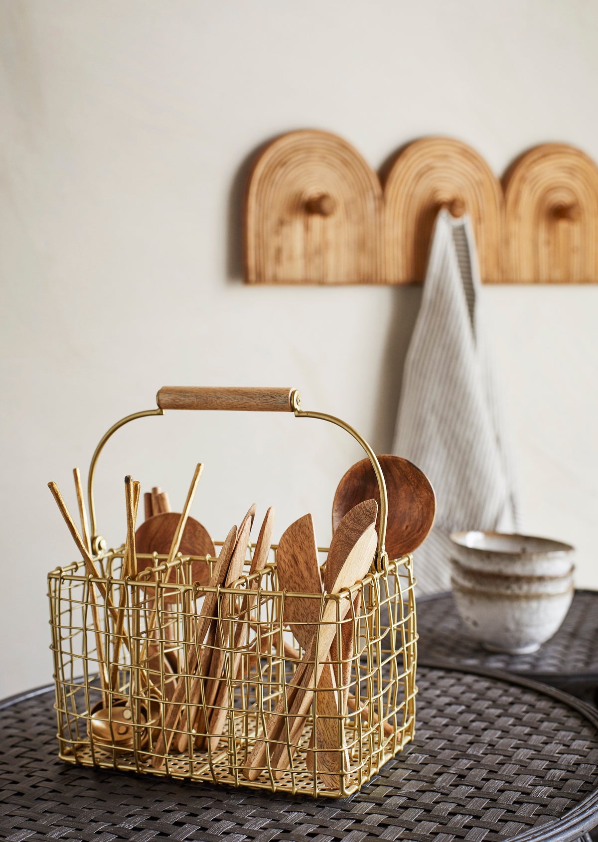 mango wood serving spoon displayed in gold wire utensil basket in kitchen