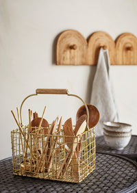 mango wood serving spoon displayed in gold wire utensil basket in kitchen