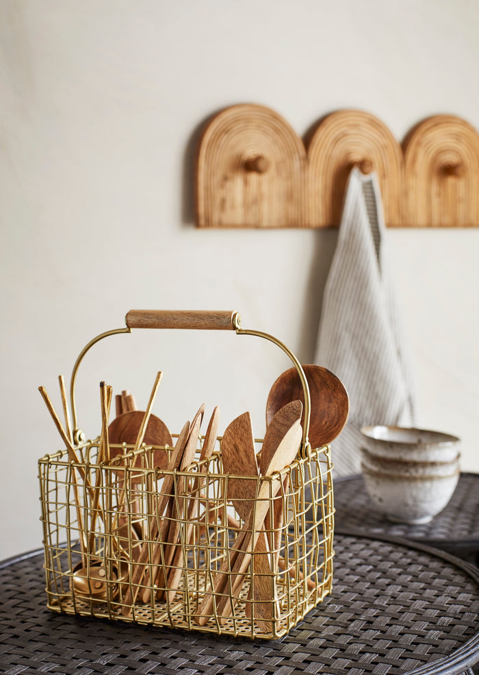 mango wood serving spoon displayed in gold wire utensil basket in kitchen