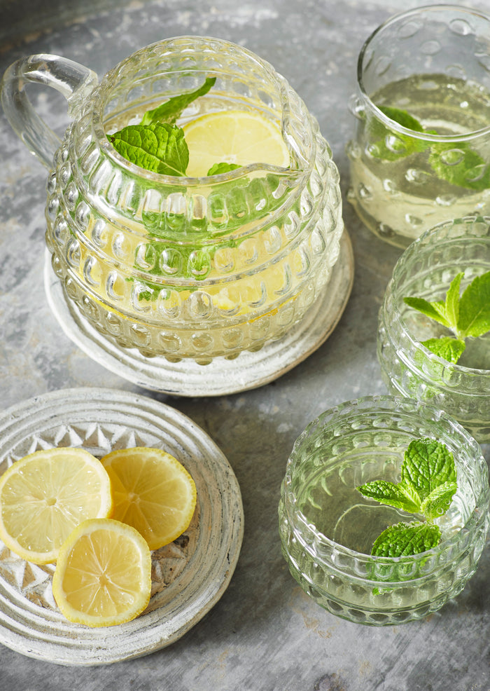 dotted glass jug filled with lemon and mint water on rustic table
