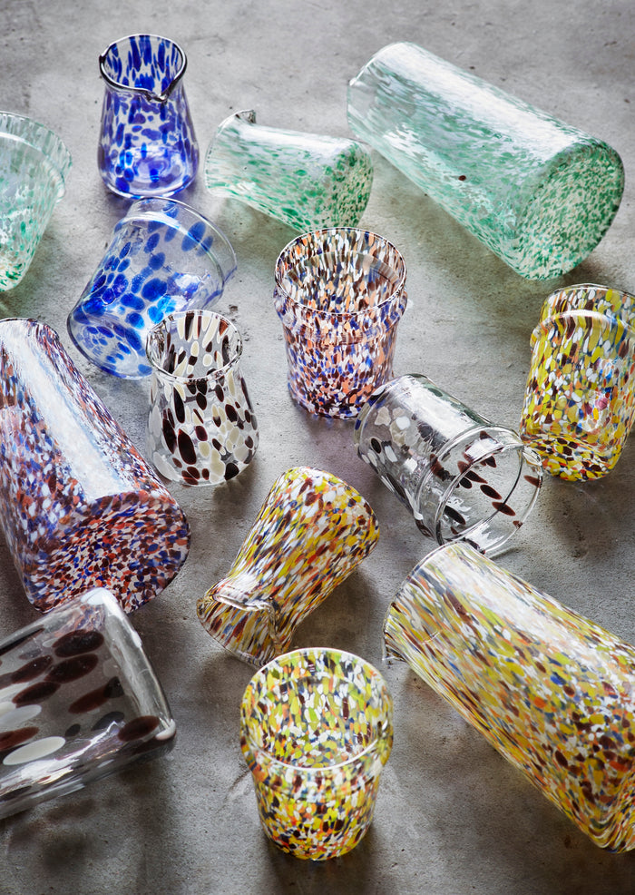 assorted handmade glass jugs and tumblers with colourful speckled patterns
