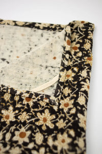 Close-up of the cream and ochre flowers on the Nadine black kitchen towel by Olsson & Jensen