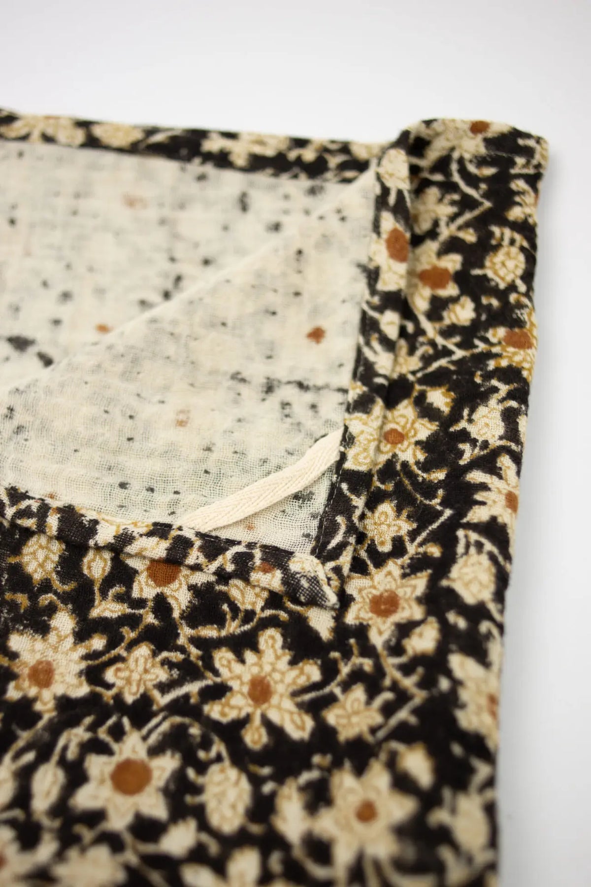 Close-up of the cream and ochre flowers on the Nadine black kitchen towel by Olsson & Jensen