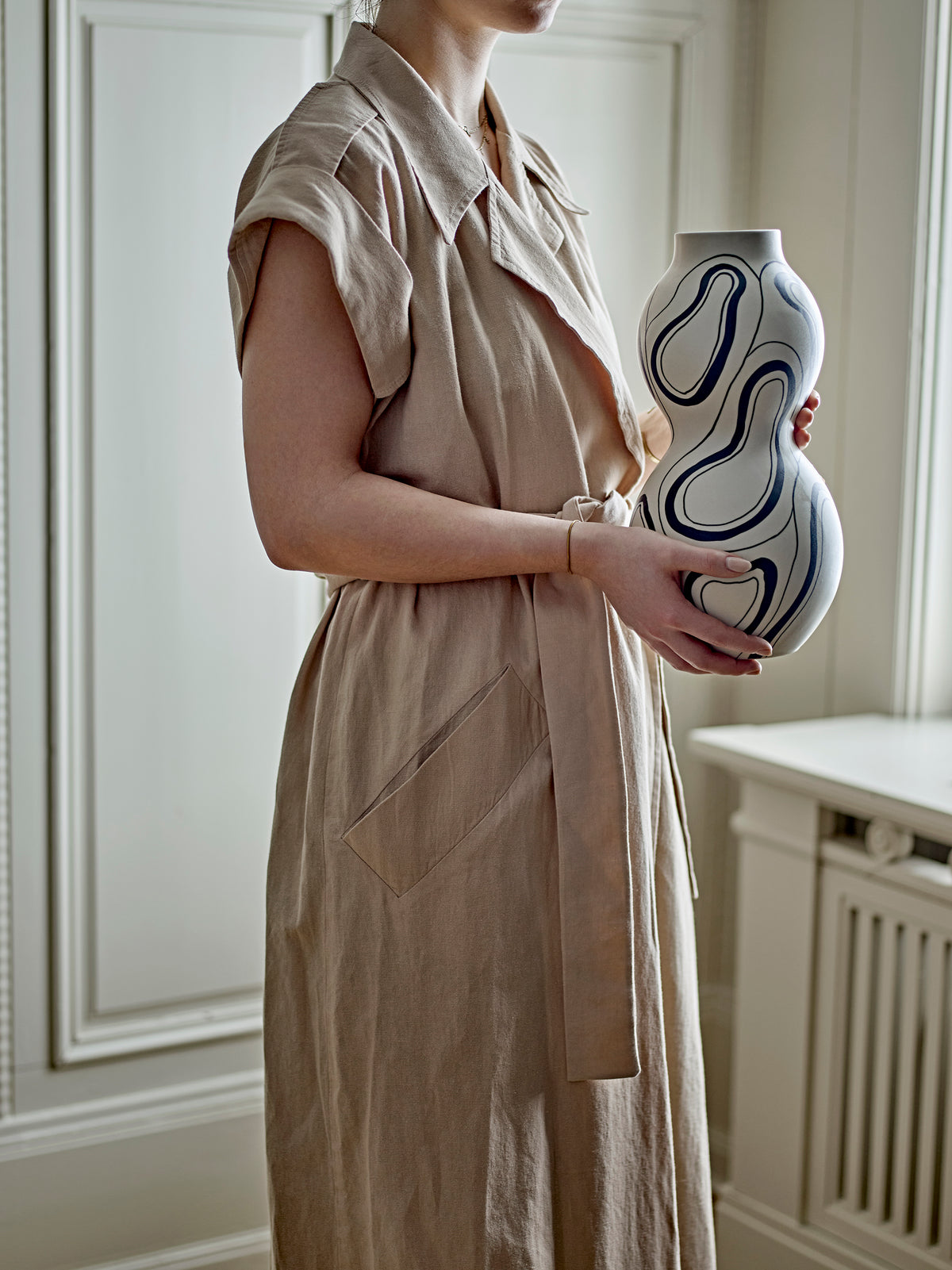 Person holding tall sculptural black and white stoneware vase