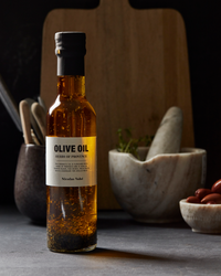 Nicolas Vahé Herbes de Provence olive oil 25cl on kitchen counter with herbs and mortar in background.