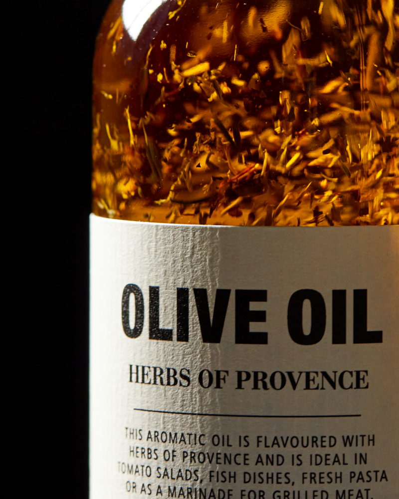 Close-up of Herbes de Provence olive oil label with visible herbs in extra virgin olive oil.
