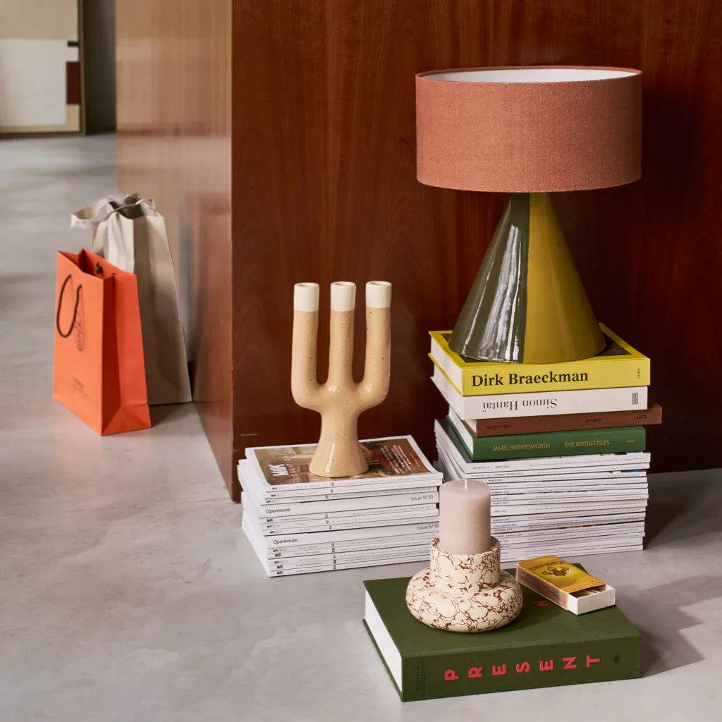 Nox candle holder styled on stacked books beside a table lamp