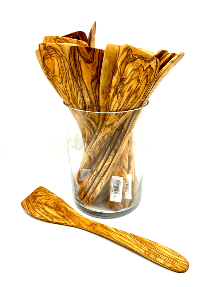 Glass jar filled with olive wood spatulas with one spatula in the foreground