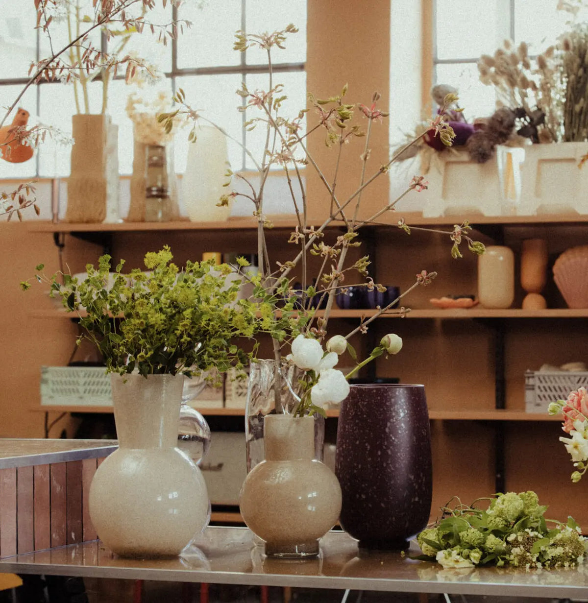 Olsson & Jensen glass vases and jugs styled with fresh stems on open shelving