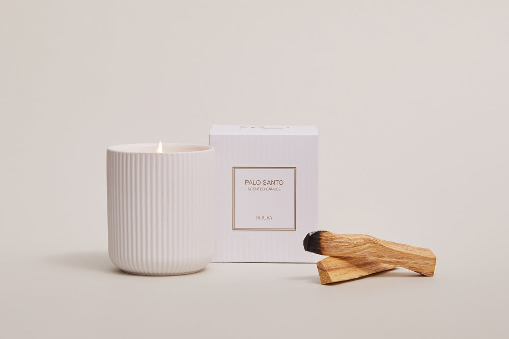 Palo Santo ceramic candle lit beside boxed packaging and palo santo wood