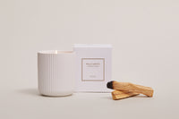 Palo Santo ceramic candle lit beside boxed packaging and palo santo wood